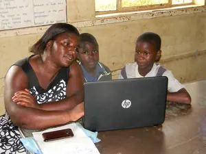 African Teacher Helping Children On A Laptop ?? title