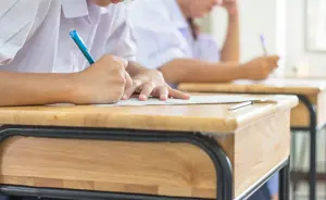 Image Of School Desk And Pupil Writing